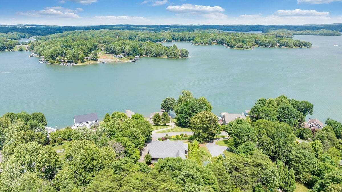 A lakeside property with multiple houses, a dock, and lush greenery.