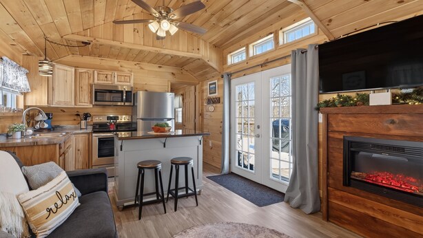 Un intérieur de chalet chaleureux comprenant une cuisine, un coin repas et une cheminée.