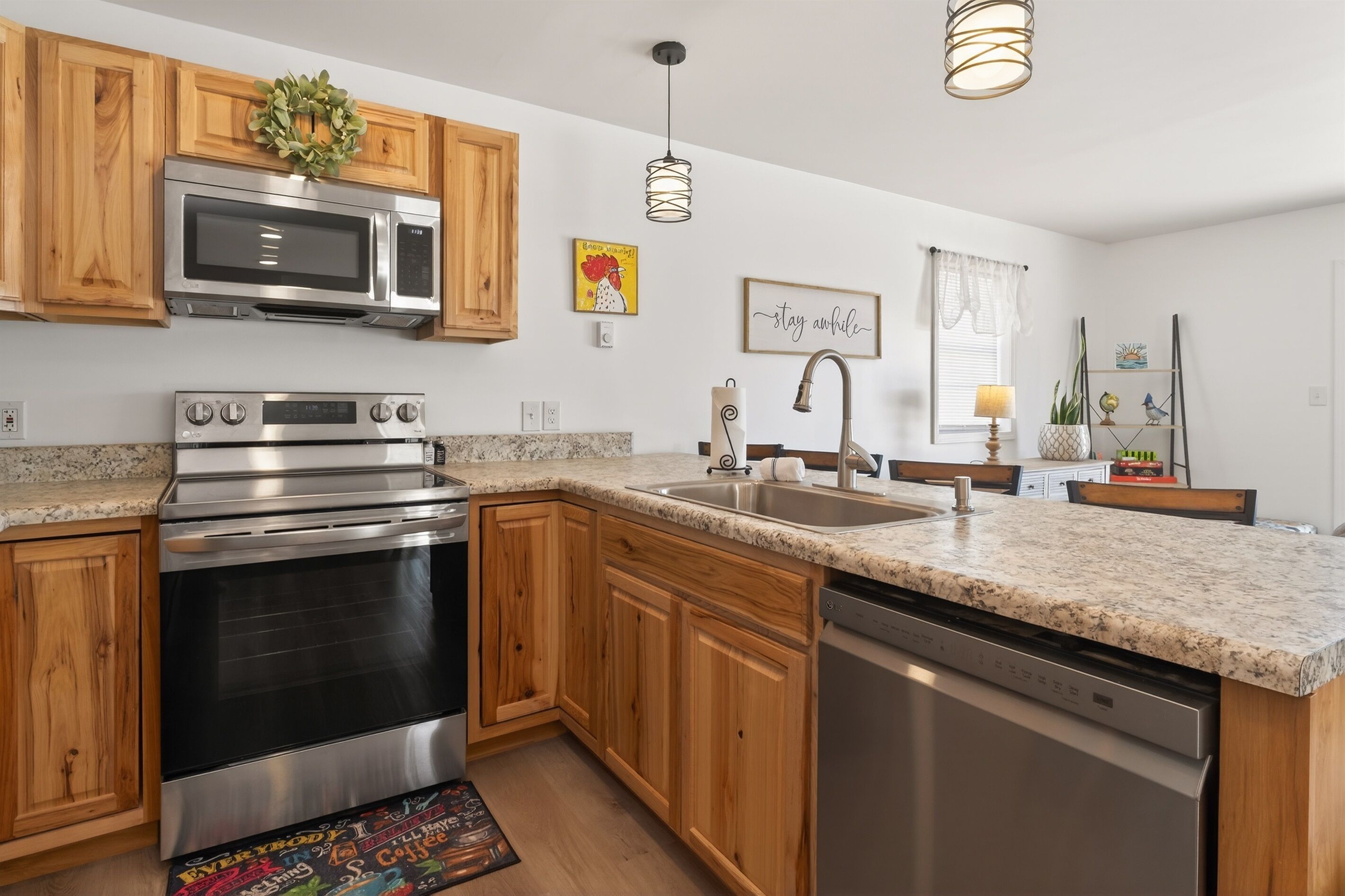 A modern kitchen with wooden cabinets, stainless steel appliances, granite countertops, and a farmhouse sink.
