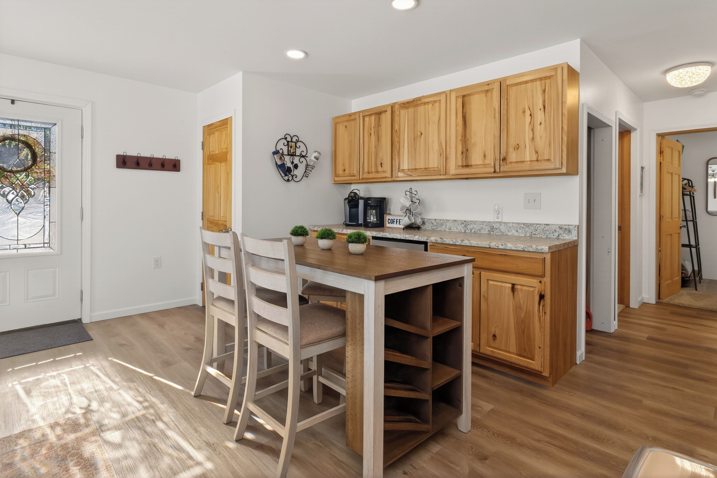 Una cucina moderna con mobili in legno, un piano di lavoro in granito e una zona pranzo con tavolo e sedie.