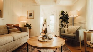 Una sala acogedora con una mesa de centro de madera, un sofá, un sillón y una lámpara.