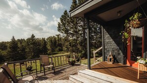 Una terraza de madera con asientos exteriores y vistas a un bosque.