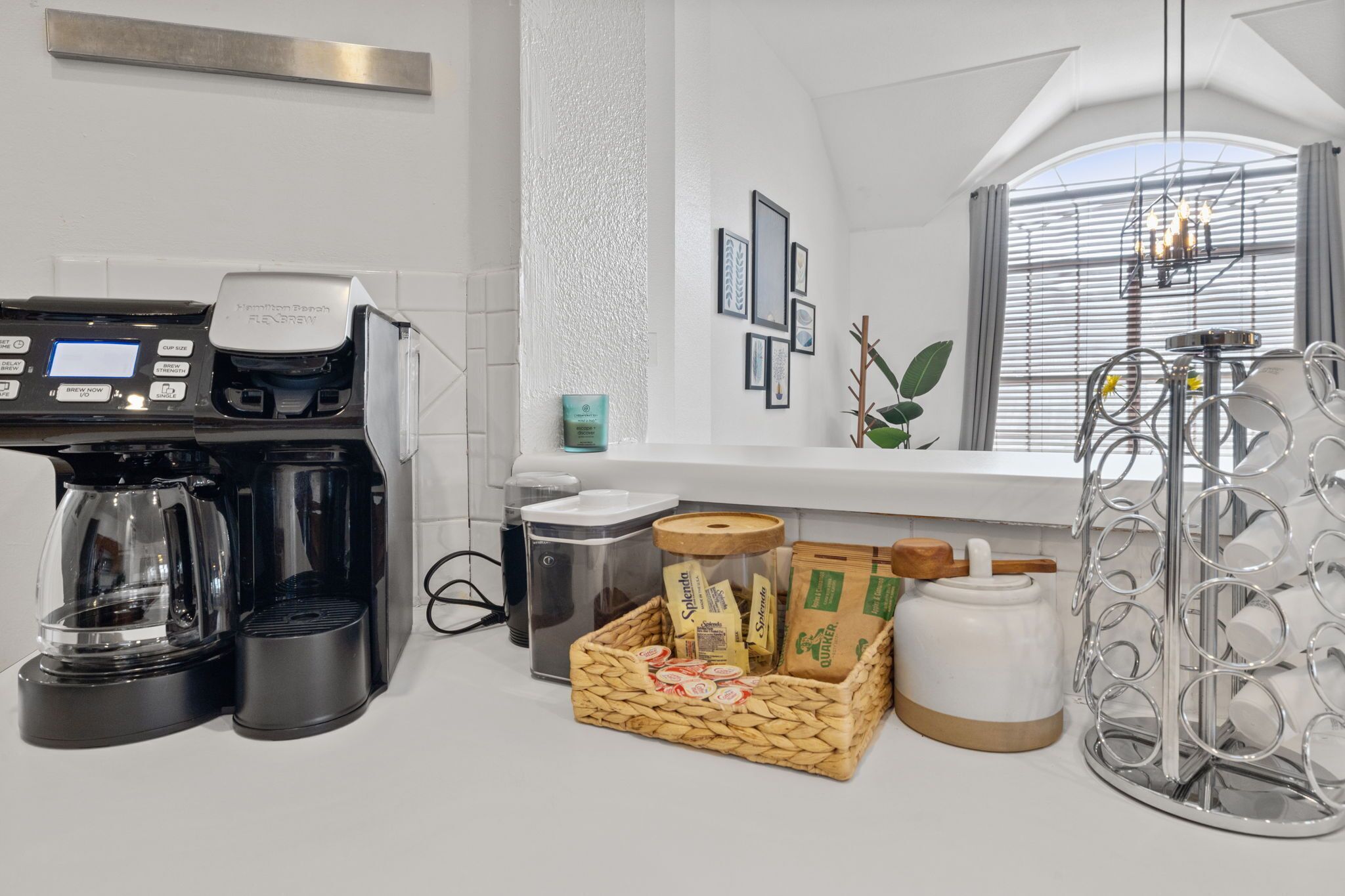 A modern kitchen with a coffee maker, a basket of snacks, and a decorative metal rack.