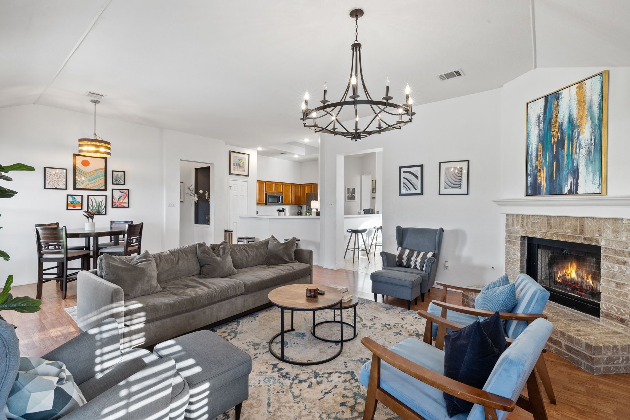A modern living room with a fireplace, a dining area, and a kitchen in the background.