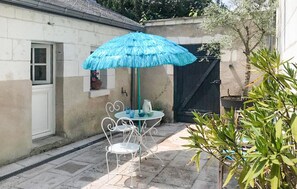 A patio with a table and chairs, a blue umbrella, and potted plants. - Awesome home in Loches with WiFi (Loches)