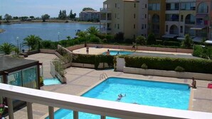 A swimming pool surrounded by a landscaped area with buildings in the background. - Pleasant studio cabin apartment in residence with pool near Richelieu beach, Cap d'Agde (LE CAP D AGDE)