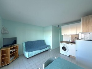 A compact living space with a sofa, a television, a washing machine, and a refrigerator. - CAP D'AGDE - Plage Richelieu / Réf 161 (CAP D'AGDE)