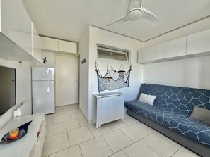 A compact living space with a kitchenette, a sofa, a ceiling fan, and a hanging macrame piece. - CAP D'AGDE - Les Falaises / Réf 146 (CAP D'AGDE)