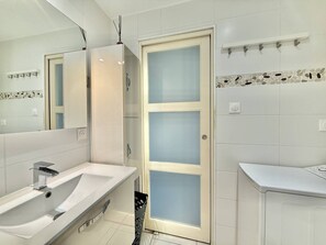 A modern bathroom with a white sink, a mirror, and a frosted glass door. - CAP D'AGDE - Les Falaises / Réf 146 (CAP D'AGDE)