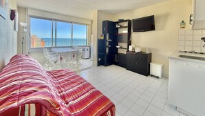 Un estudio pequeño con cama, kitchenette y balcón con vistas al mar.