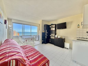 Ein kompaktes Studioapartment mit Bett, Küchenzeile und einem Balkon mit Meerblick.