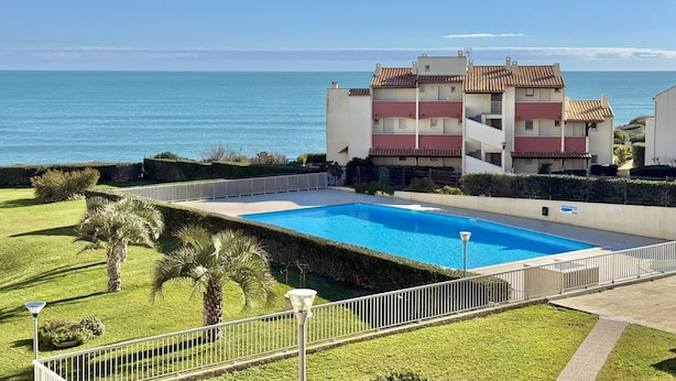 Edificio residencial con piscina, vistas al mar y césped cuidado.