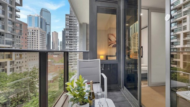Een balkon met een tafeltje voor twee personen, een plant in pot en een fles champagne.