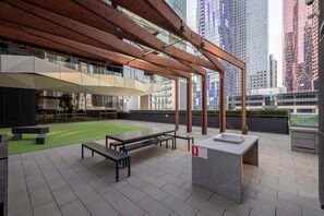 Eine Außenterrasse mit Holz-Pergola, Sitzbereichen und einem kleinen Tisch.