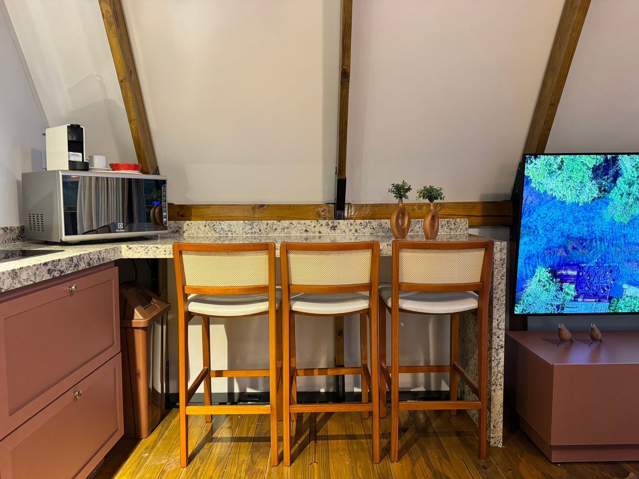 A kitchen with wooden chairs, a microwave, and a television.