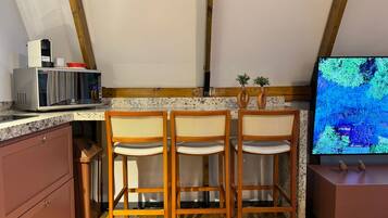 A kitchen with wooden chairs, a microwave, and a television.