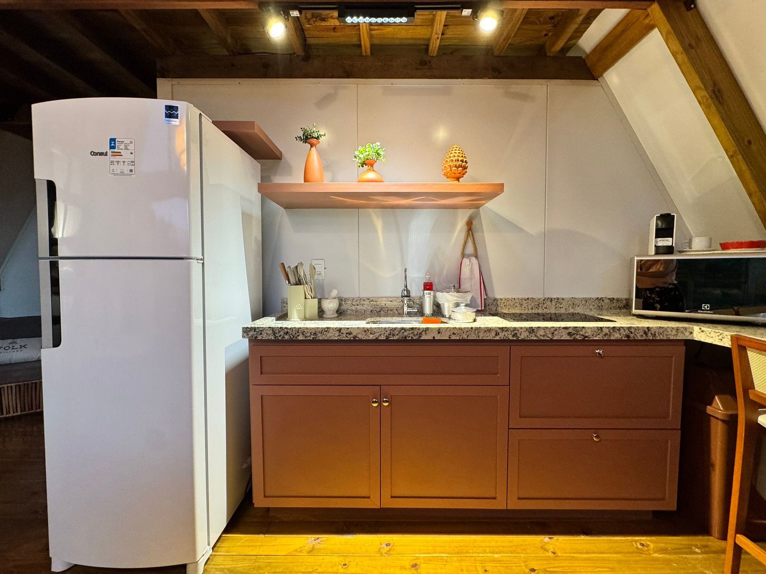 A kitchen with a white refrigerator, wooden cabinets, a granite countertop, and a microwave.