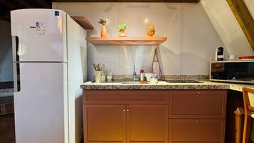 A kitchen with a white refrigerator, wooden cabinets, a granite countertop, and a microwave.