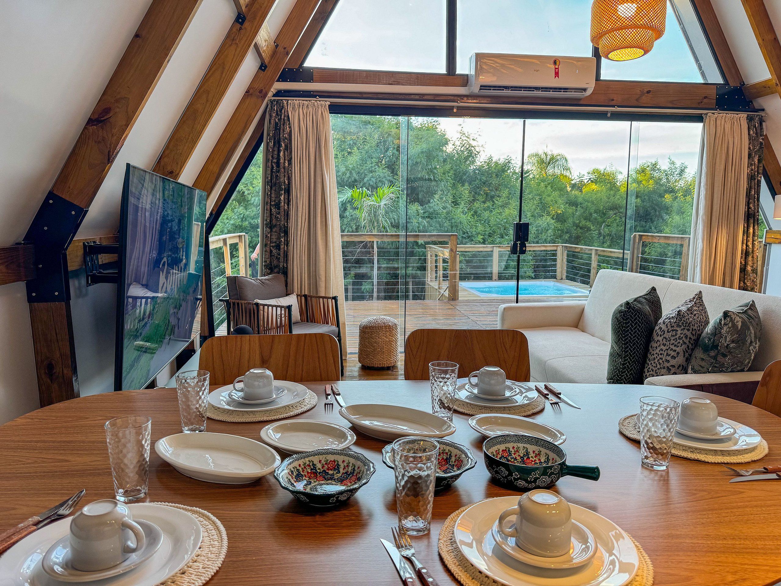 Un coin repas avec une table dressée pour quatre personnes, un canapé et une vue sur une piscine.