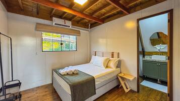 Quarto com cama, janela, aparelho de ar condicionado, espelho e teto de madeira.