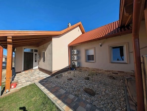 Uma casa com telhado de cerâmica, varanda coberta e entrada de automóveis em cascalho.