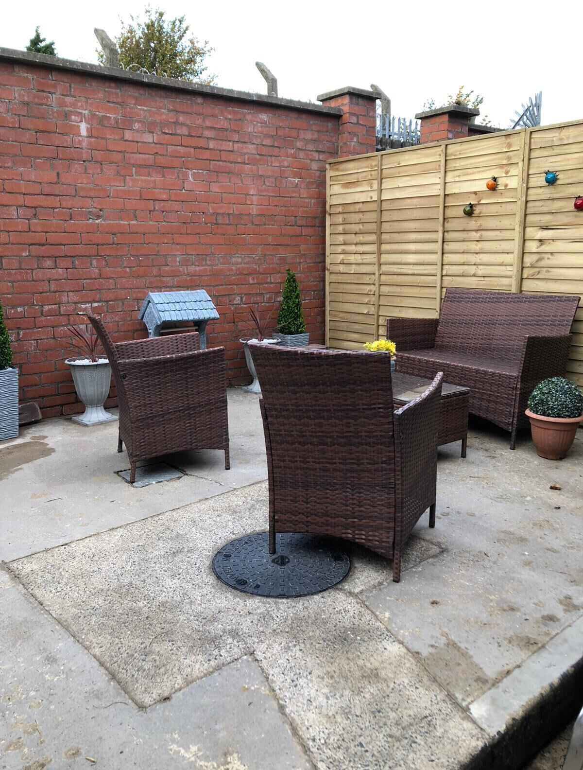 A patio area with wicker furniture, a brick wall, and a wooden gate.