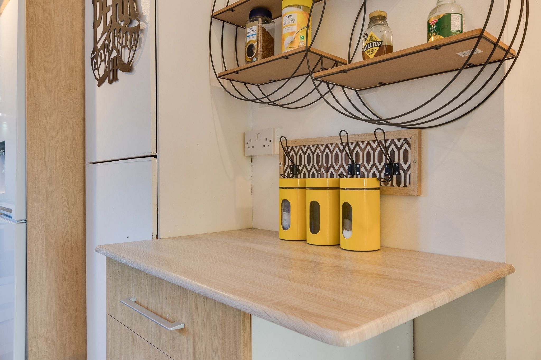 A kitchen with a wooden countertop, a built-in refrigerator, and shelves with jars and containers.