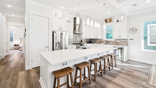 A modern kitchen with white cabinetry, a large island with stools, stainless steel appliances, and pendant lighting. - Highland Parks, Resort-Style Pool! LSV/Golf Cart & 6 Bikes! (Santa Rosa Beach)