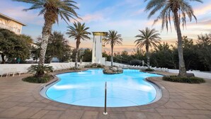 A swimming pool with palm trees, lounge chairs, and a modern building in the background. - Highland Parks, Resort-Style Pool! LSV/Golf Cart & 6 Bikes! (Santa Rosa Beach)