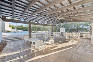 An outdoor patio area with a pool, covered seating, and a grill station. - Highland Parks, Resort-Style Pool! LSV/Golf Cart & 6 Bikes! (Santa Rosa Beach)