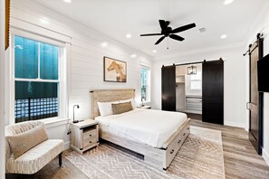 A bedroom with a large bed, a wooden headboard, a nightstand, a bench, a ceiling fan, and a sliding closet door. - Highland Parks, Resort-Style Pool! LSV/Golf Cart & 6 Bikes! (Santa Rosa Beach)