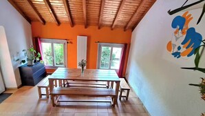 A dining area with a wooden table and benches, orange walls, and a ceiling with exposed beams. - CHEZ INES A place to live in Arbois - 2 to 10 pers ARBOIS (Arbois)