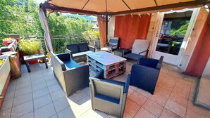 An outdoor patio with wicker furniture, a table, and a covered area. - CHEZ INES A place to live in Arbois - 2 to 10 pers ARBOIS (Arbois)