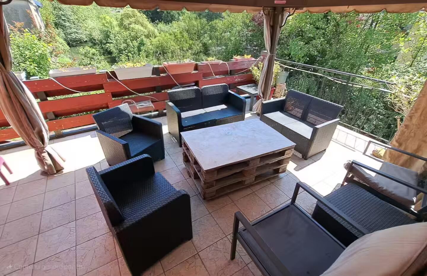 Eine Außenpatio-Terrasse mit Korbmöbeln, einem Holztisch und einem Laptop auf dem Tisch.
