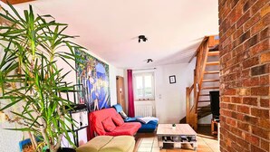 A cozy loft-style living space with a wooden staircase, a large potted plant, a colorful mural, and a red sofa. - CHEZ INES A place to live in Arbois - 2 to 10 pers ARBOIS (Arbois)