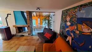A living room with a fireplace, a sofa, a painting, and a staircase leading to an upper level. - CHEZ INES A place to live in Arbois - 2 to 10 pers ARBOIS (Arbois)