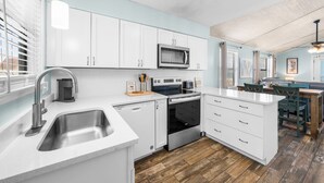 Una cocina moderna con armarios blancos, electrodomésticos de acero inoxidable y piso de madera.