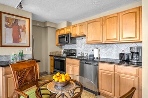 A kitchen with wooden cabinets, a microwave, a coffee maker, and a dishwasher. - Kaanapali Shores | Ocean View Studio | Car Incl. w/ 6+ Nights | KS-736 by KBM (Lahaina)