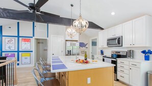 A modern kitchen with white cabinets, a central island, a ceiling fan, and a chandelier. - Explore Mayberry: 2 King Masters, 3 Bed / 3 Bath, Fire Pit (Mount Airy)