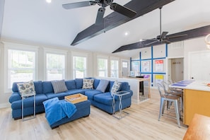 A modern living room with a blue sofa, a small table, and a kitchen area with a bar.