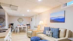 A modern living room with a sofa, ottomans, a coffee table, and a dining area with chairs and a table. - Explore Mayberry: 2 King Masters, 3 Bed / 3 Bath, Fire Pit (Mount Airy)
