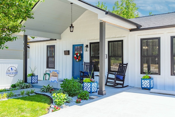 A white building with a porch, a blue door, and a sign that reads 'Explore Mayberry.'