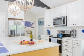 A modern kitchen with white cabinetry, a stainless steel refrigerator, a microwave, and a gas stove.
