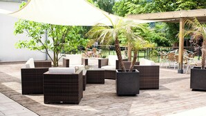 An outdoor seating area with wicker furniture and planters. - Conference Partner Ullrich (Elfershausen)