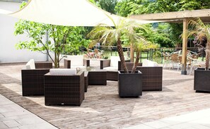 An outdoor seating area with wicker furniture and planters. - Conference Partner Ullrich (Elfershausen)