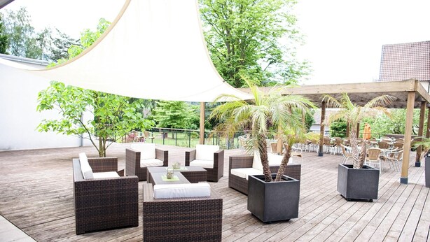 An outdoor patio area with wicker furniture and potted plants. - Conference Partner Ullrich (Elfershausen)