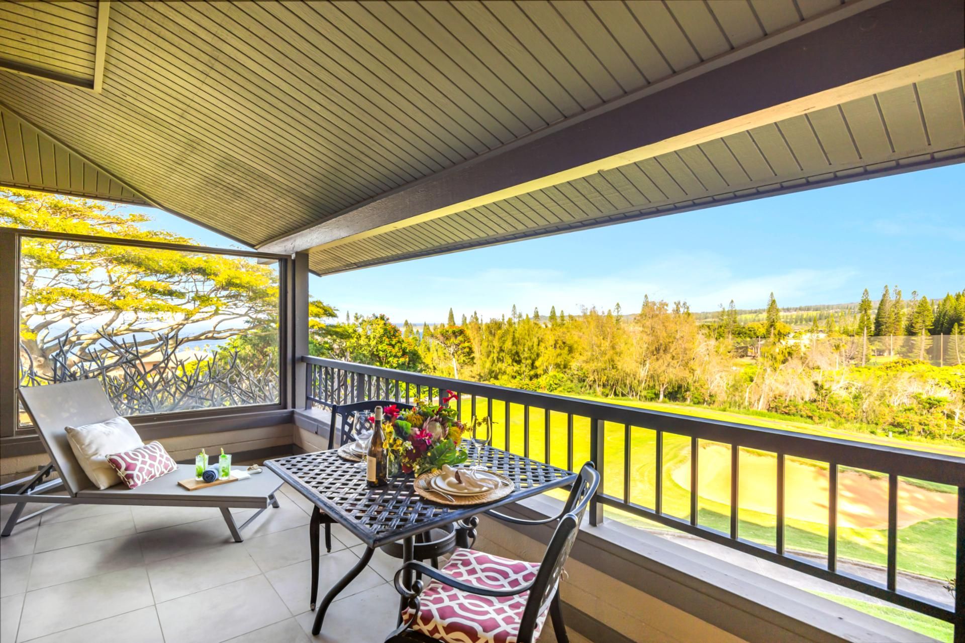 A balcony with a table, chairs, and a view of a golf course.