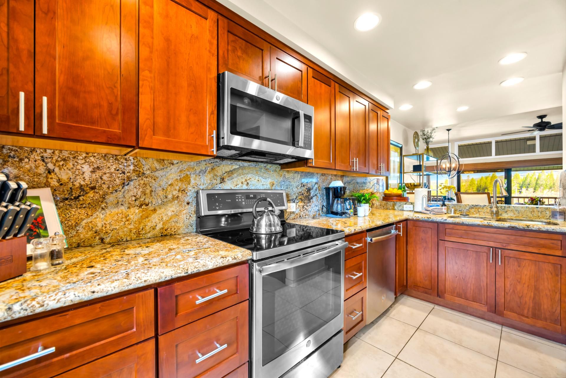 A kitchen with wooden cabinets, granite countertops, stainless steel appliances, and a view of the outdoors.