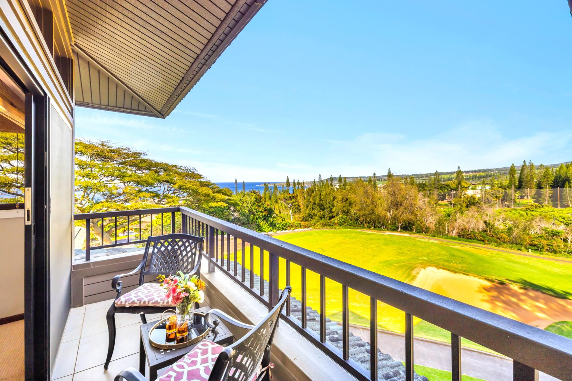 Ein Balkon mit Blick auf einen Golfplatz, ein Tisch mit Stühlen und eine Vase mit Blumen.