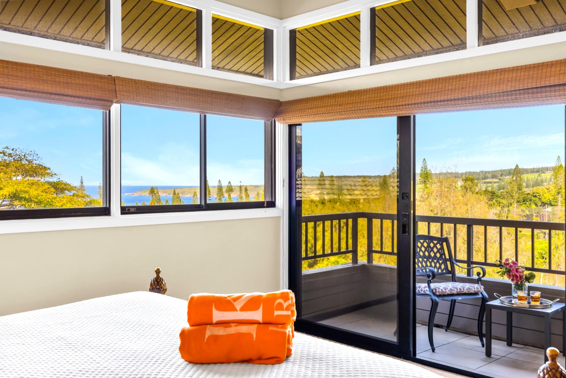 Una camera da letto con un letto grande, un balcone con tavolo e sedie, e vista sul paesaggio.